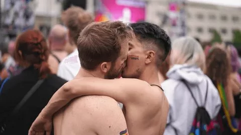 Deux hommes s’embrassent lors d’une marche des fiertés, symbole de la liberté et de la culture gay associée à l’usage responsable des poppers.